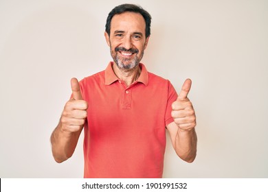 Middle age hispanic man wearing casual clothes success sign doing positive gesture with hand, thumbs up smiling and happy. cheerful expression and winner gesture. 