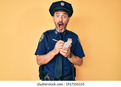 Middle Age Hispanic Man Wearing Police Uniform Writing Traffic Fine Afraid And Shocked With Surprise And Amazed Expression, Fear And Excited Face. 