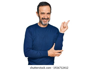 Middle age hispanic man wearing casual clothes with a big smile on face, pointing with hand and finger to the side looking at the camera.  - Shutterstock ID 1926712412