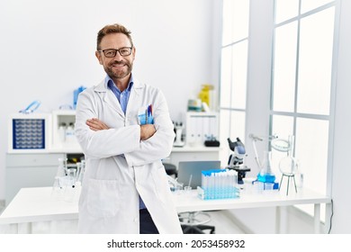 Middle age hispanic man wearing scientist uniform with arms crossed gesture at laboratory - Powered by Shutterstock