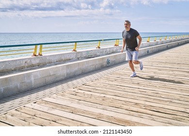 Middle Age Hispanic Man Wearing Sportswear Running At Seaside