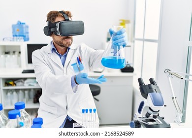 Middle age hispanic man wearing scientist uniform using vr glasses holding test tube at laboratory - Powered by Shutterstock