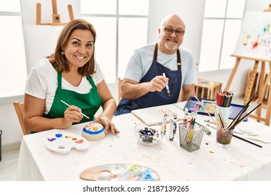 Middle Age Hispanic Painter Couple Smiling Happy Painting At Art Studio.