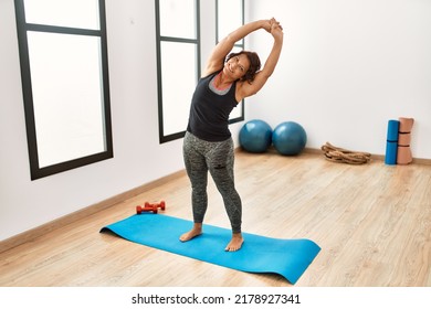 Middle Age Hispanic Sporty Woman Smiling Happy Stretching At Sport Center.