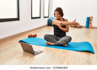 Middle Age Hispanic Sporty Woman Having Online Fitness Class At Sport Center.