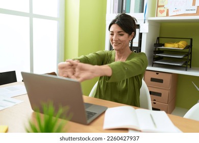 Middle age hispanic woman business worker using laptop stretching arms at office - Powered by Shutterstock