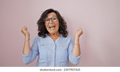 Middle age hispanic woman celebrating over isolated pink background - Powered by Shutterstock