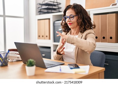 Middle Age Hispanic Woman Doing Video Call Using Sign Language At The Office