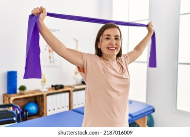 Middle age hispanic woman doing exercise with elastic bands at physiotherapy clinic - Powered by Shutterstock