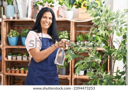 Middle age hispanic woman florist using diffuser working at florist