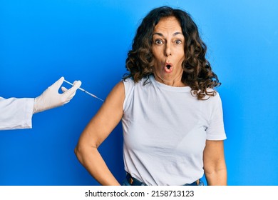 Middle Age Hispanic Woman Getting Vaccine Scared And Amazed With Open Mouth For Surprise, Disbelief Face 