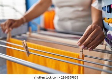 Middle Age Hispanic Woman Hanging Clothes On Clothesline At Laundry Room