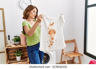 Middle Age Hispanic Woman Holding Dirty T Shirt At Laundry Room