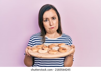 Middle Age Hispanic Woman Holding Sweet Pastries Depressed And Worry For Distress, Crying Angry And Afraid. Sad Expression. 