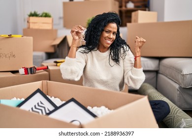 Middle Age Hispanic Woman Holding Keys Of New Home Screaming Proud, Celebrating Victory And Success Very Excited With Raised Arm 