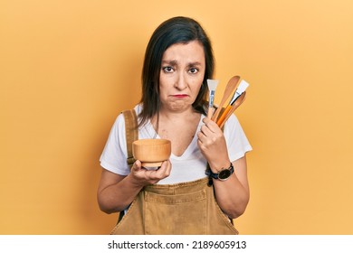 Middle Age Hispanic Woman Holding Makeup Tools Depressed And Worry For Distress, Crying Angry And Afraid. Sad Expression. 