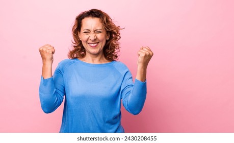 middle age hispanic woman looking extremely happy and surprised, celebrating success, shouting and jumping - Powered by Shutterstock