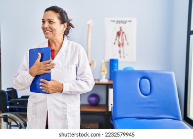 Middle age hispanic woman physiotherapist holding clipboard at rehab clinic - Powered by Shutterstock