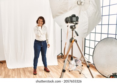 Middle Age Hispanic Woman Posing As Model At Photography Studio Looking Stressed And Nervous With Hands On Mouth Biting Nails. Anxiety Problem. 