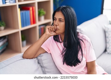 Middle Age Hispanic Woman Sitting On Sofa With Serious Expression At Home