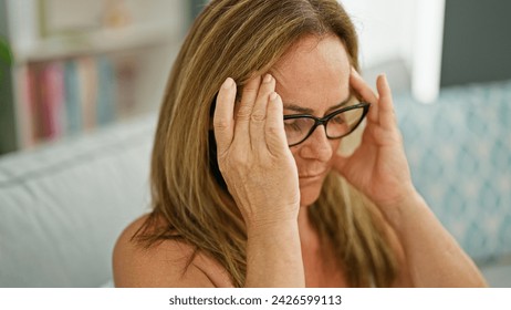 Middle age hispanic woman sitting on sofa suffering for headache at home - Powered by Shutterstock