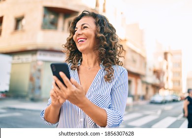 Middle Age Hispanic Woman Smiling Happy And Using Smartphone At The City.