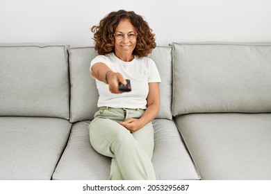 Middle Age Hispanic Woman Smiling Confident Watching Tv At Home