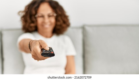 Middle Age Hispanic Woman Smiling Confident Watching Tv At Home