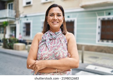 Middle age hispanic woman smiling confident standing with arms crossed gesture at street - Powered by Shutterstock