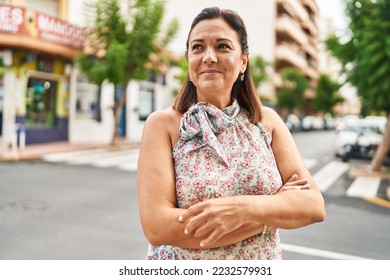 Middle age hispanic woman smiling confident standing with arms crossed gesture at street - Powered by Shutterstock