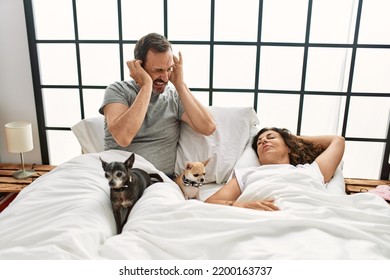 Middle age hispanic woman snoring and man angry covering ears at bedroom. - Powered by Shutterstock