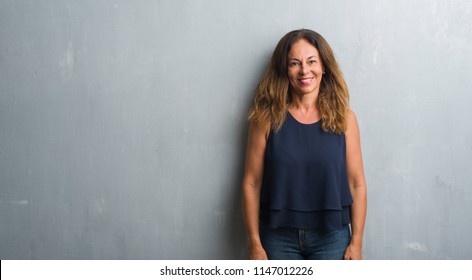 Middle Age Hispanic Woman Standing Over Grey Grunge Wall With A Happy And Cool Smile On Face. Lucky Person.