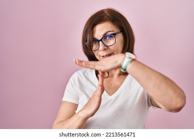 Middle Age Hispanic Woman Standing Over Pink Background Doing Time Out Gesture With Hands, Frustrated And Serious Face 