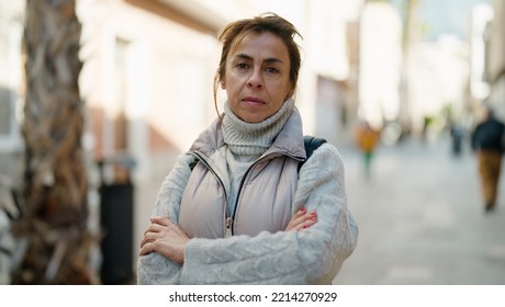 Middle Age Hispanic Woman Standing With Serious Expression And Arms Crossed Gesture At Street