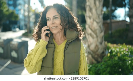 Middle age hispanic woman talking on smartphone with serious expression at park - Powered by Shutterstock