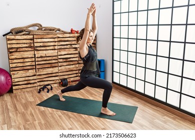 Middle Age Hispanic Woman Training Yoga At Sport Center