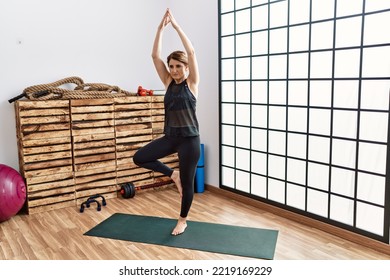 Middle Age Hispanic Woman Training Yoga At Sport Center