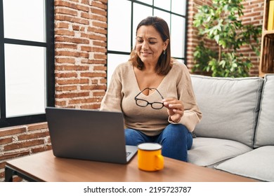 Middle Age Hispanic Woman Using Laptop And Drinking Coffee At Home