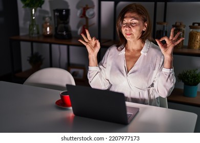 Middle Age Hispanic Woman Using Laptop At Home At Night Relax And Smiling With Eyes Closed Doing Meditation Gesture With Fingers. Yoga Concept. 