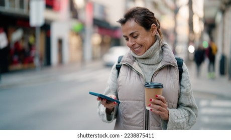 Middle age hispanic woman using smartphone drinking coffee at street - Powered by Shutterstock