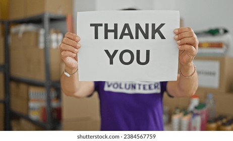 Middle age hispanic woman volunteer holding thank you message at charity center