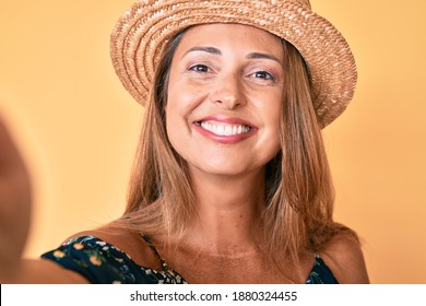 Middle Age Hispanic Woman Wearing Summer Hat Taking A Selfie Smiling With A Happy And Cool Smile On Face. Showing Teeth. 