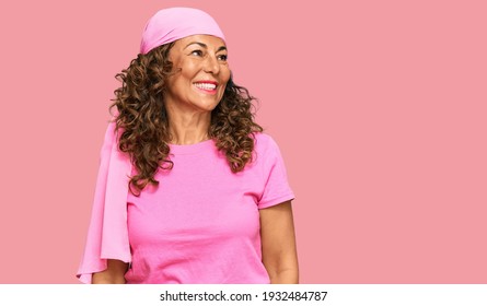 Middle Age Hispanic Woman Wearing Breast Cancer Support Pink Scarf Looking Away To Side With Smile On Face, Natural Expression. Laughing Confident. 