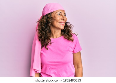 Middle Age Hispanic Woman Wearing Breast Cancer Support Pink Scarf Looking Away To Side With Smile On Face, Natural Expression. Laughing Confident. 