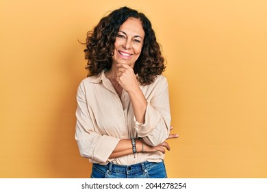 Middle age hispanic woman wearing casual clothes looking confident at the camera smiling with crossed arms and hand raised on chin. thinking positive.  - Shutterstock ID 2044278254