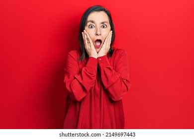 Middle age hispanic woman wearing casual clothes afraid and shocked, surprise and amazed expression with hands on face 
