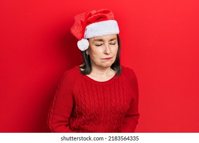 Middle Age Hispanic Woman Wearing Christmas Hat With Hand On Stomach Because Indigestion, Painful Illness Feeling Unwell. Ache Concept. 