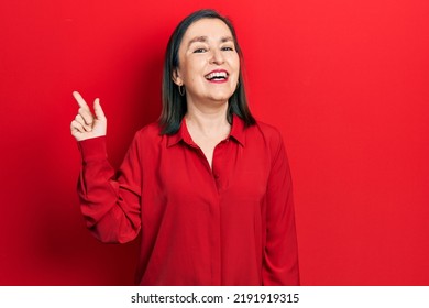 Middle Age Hispanic Woman Wearing Casual Clothes With A Big Smile On Face, Pointing With Hand Finger To The Side Looking At The Camera. 