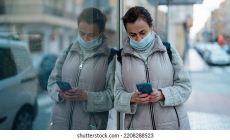 Middle Age Hispanic Woman Wearing Medical Mask Using Smartphone At Street