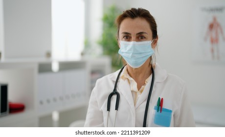 Middle Age Hispanic Woman Wearing Doctor Uniform And Medical Mask At Clinic